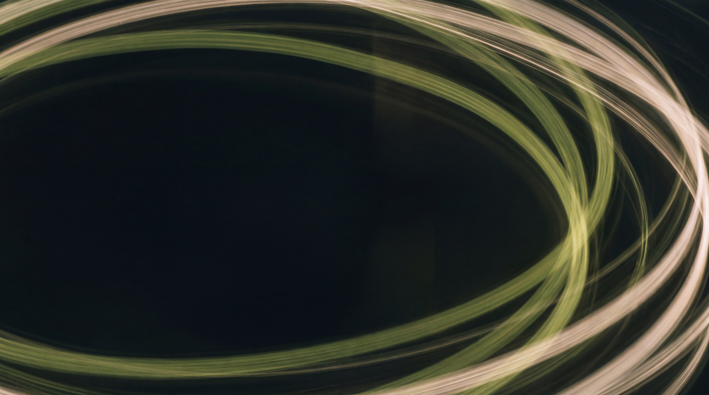 Long-exposure light trails in olive and warm white on a dark background