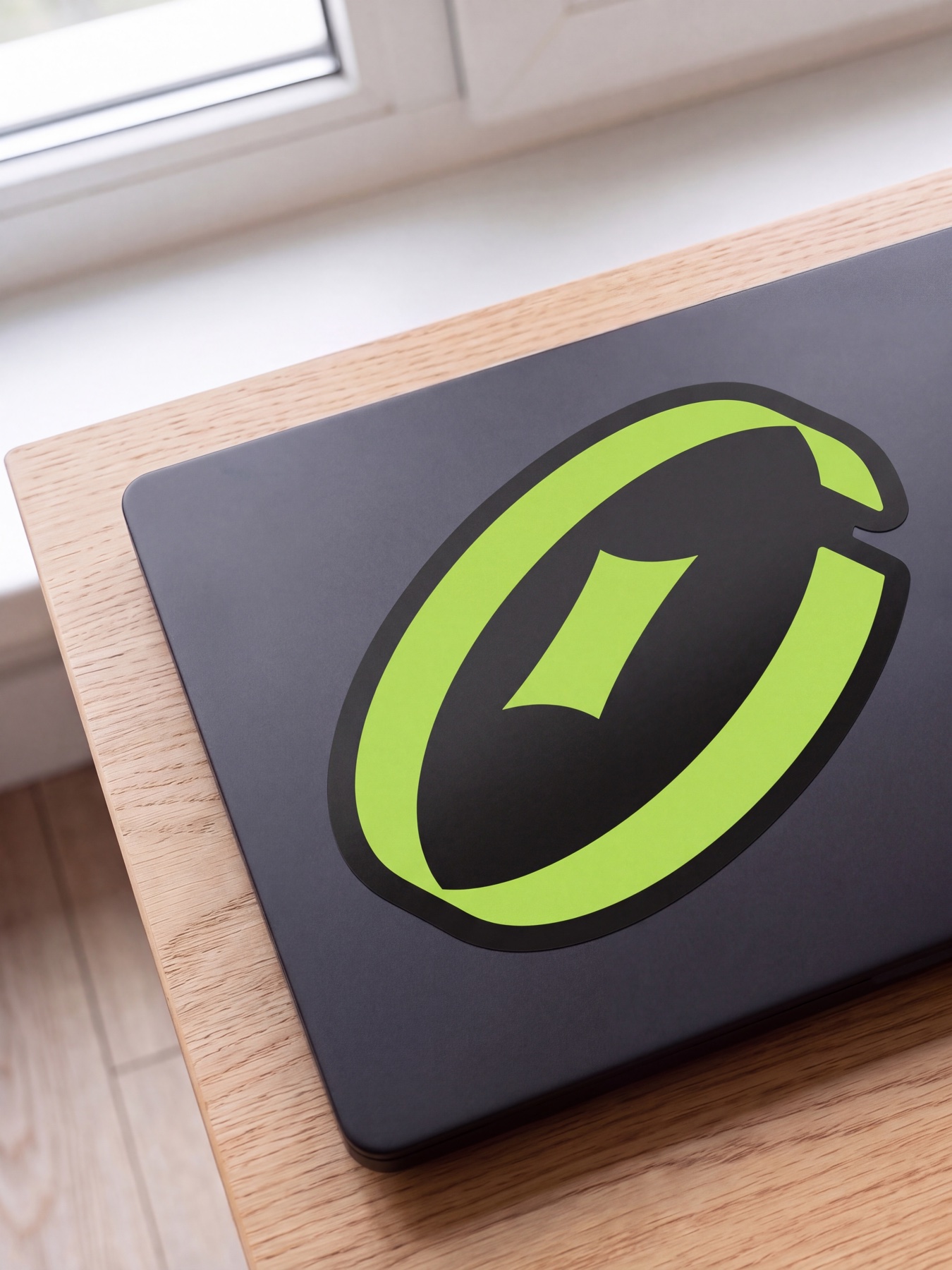 Space Black laptop lid with a large die-cut sticker: the olive symbol on a Night backing